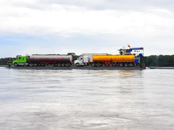 Trucks crossing a wide Amazon river on a ferry barge