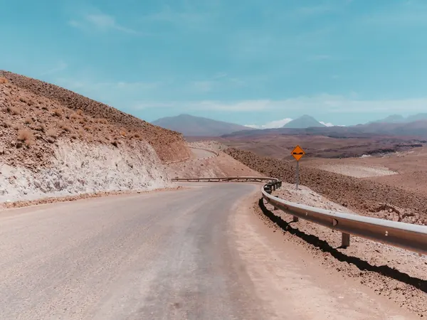 Desert road winding down through the Atacama towards Calama